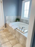 Un baño con bañera, ventana y planta en maceta.