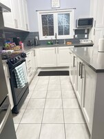 Una cocina moderna con armarios blancos, una estufa negra, un microondas y una ventana sobre el fregadero.