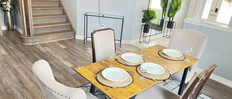 Un coin repas avec une table en bois, dressée pour quatre personnes, entourée de chaises rembourrées.