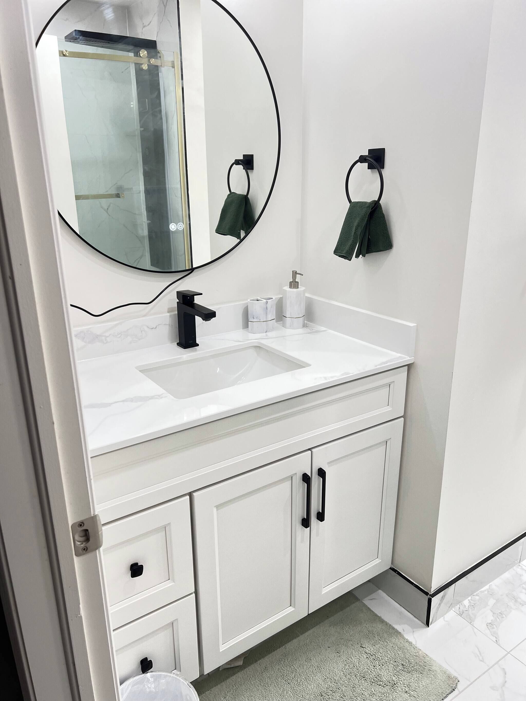 Un bagno con un mobile lavabo bianco, uno specchio, un lavandino, un porta asciugamani e un water.