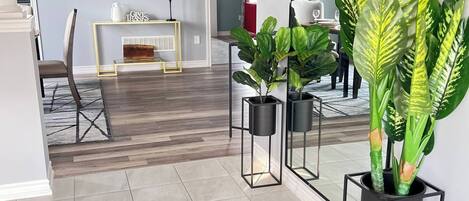 A modern living room with a large mirror, a clock, and potted plants.