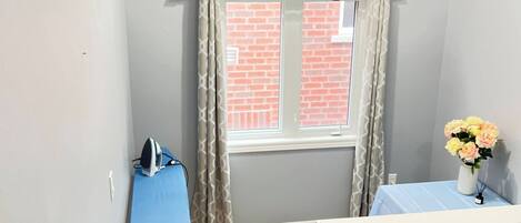A room with a window, a table with a vase of flowers, a blue tablecloth, and a red maple leaf decoration on the wall.