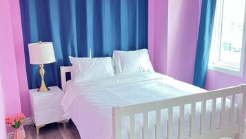 A bedroom with a bed, nightstand, lamp, chair, and a window with curtains.