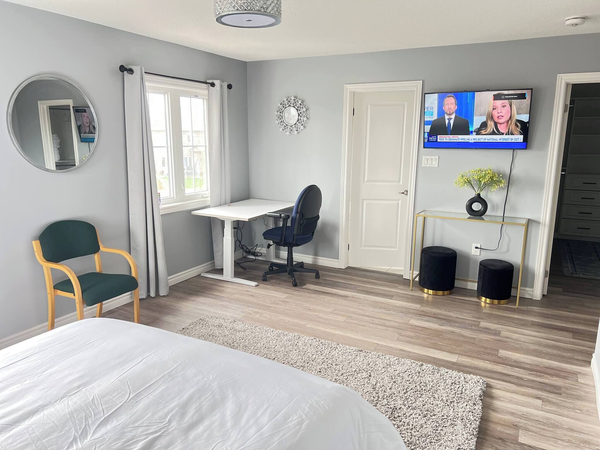 Un dormitorio con cama, escritorio, silla, televisor y puerta.