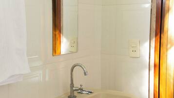 A bathroom with a pedestal sink, a mirror, and a towel hanging on the wall.