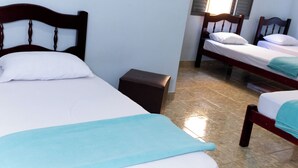 Een hotelkamer met twee enkele bedden, een klein nachtkastje en een raam met zonwering.