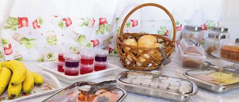 A buffet setup with various food items, including fruits, bread, and condiments.