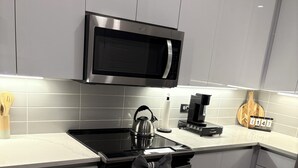 Une cuisine moderne équipée d’appareils électroménagers en acier inoxydable, d’un four à micro-ondes et d’une bouilloire.