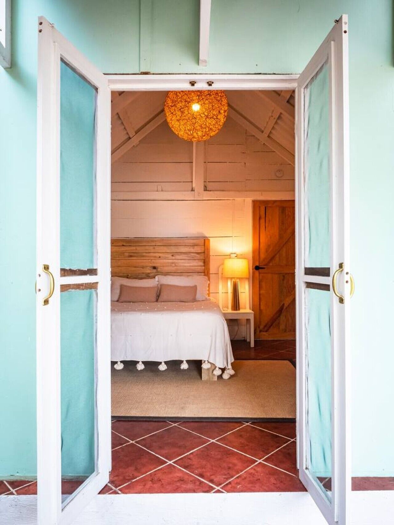 Une chambre avec un lit, une table de chevet avec une lampe et un luminaire suspendu.