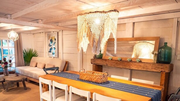 Ein Essbereich mit einem Holztisch, weißen Stühlen und einer Lampenleuchte aus Makramee.