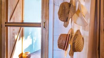 Una habitación con puerta de madera que da a un espacio con baldosas, un perchero con varios sombreros y una decoración rústica.
