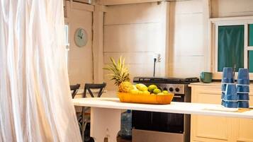 Una cocina con encimera blanca, frutero y estufa.