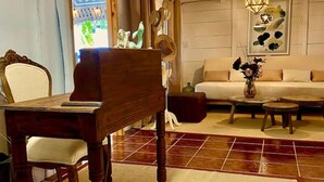 Ein Wohnzimmer mit einem Holzpiano, einem Sofa, einem Couchtisch und einer Wanddekoration.