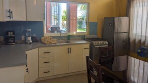 A compact kitchen with a window, a stove, a refrigerator, and a coffee maker. - Modern Beachside Retreat • Pool•Parking•Fast Wi-Fi (Playa Agua Blanca)