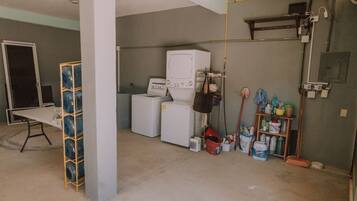 A laundry room with washing machines, a drying rack, and cleaning supplies.