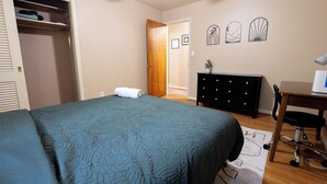 Un dormitorio con cama, armario, cómoda, escritorio y silla.