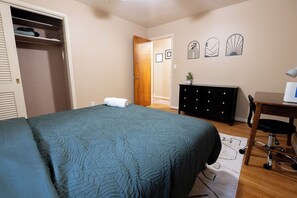 A bedroom with a bed, a dresser, a desk, and a closet.