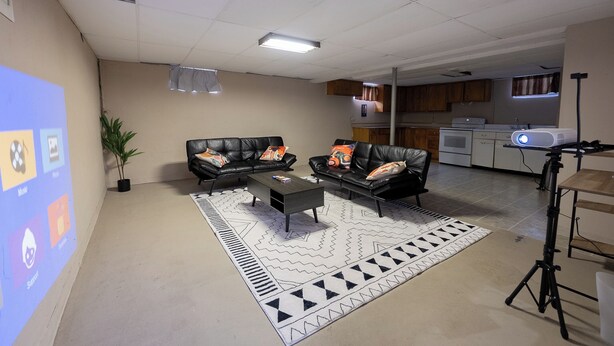 Una sala de estar con un sofá de cuero negro, una mesa de centro y una alfombra estampada.
