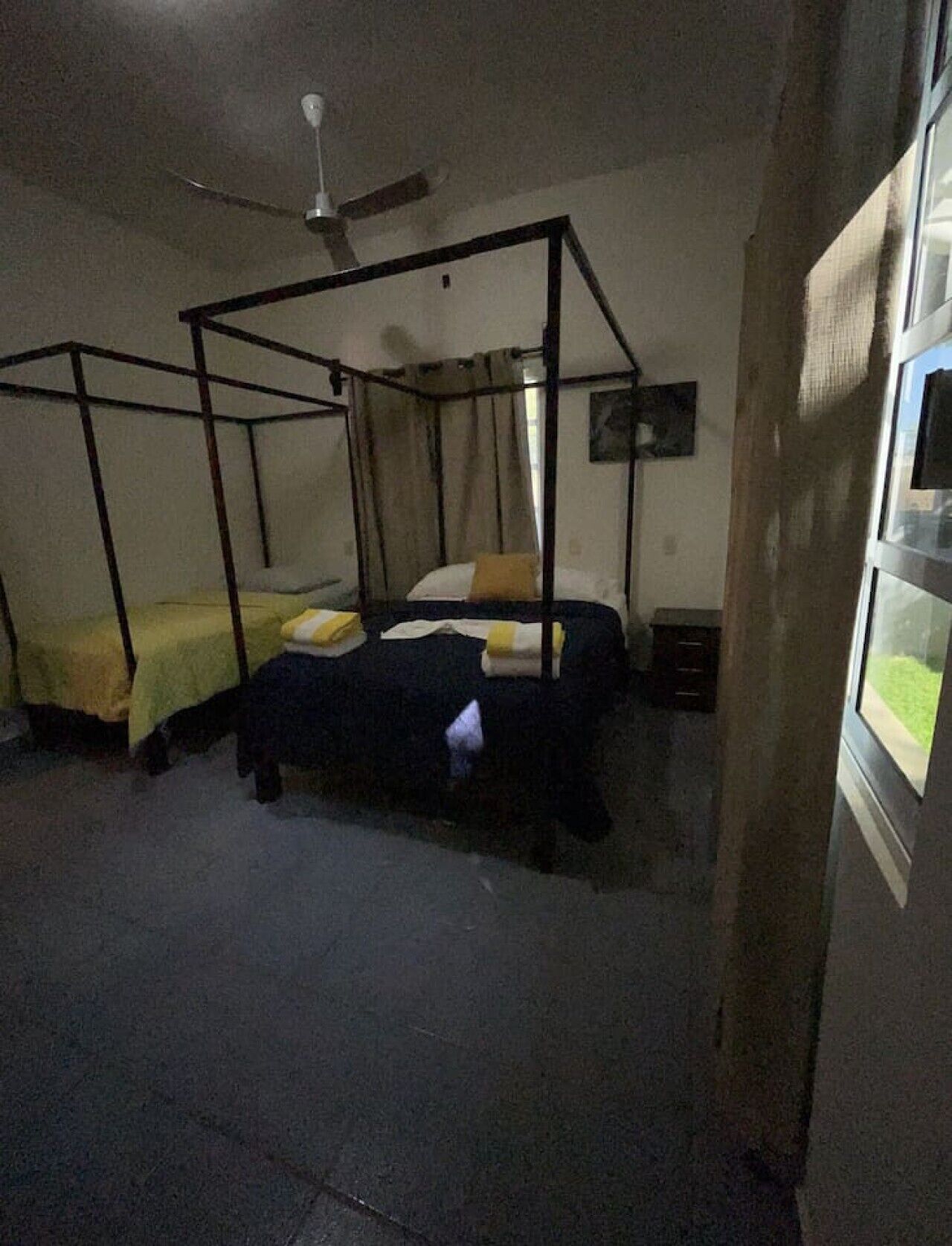 Una habitació amb dos llits, un ventilador de sostre i una finestra amb vistes.