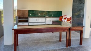 Una cocina moderna con una mesa de comedor en primer plano, un ventilador de techo y vistas al exterior.