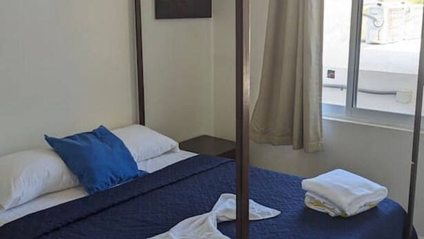 A four-poster bed with a blue bedspread, white pillows, and neatly folded towels. - Spacious 2BR/2.5BA Oceanview Casita with Terrace (Playa Agua Blanca)