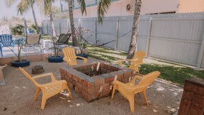 A backyard with a fire pit surrounded by chairs, a hammock, and a fenced area. - Spacious 2BR/2.5BA Oceanview Casita with Terrace (Playa Agua Blanca)