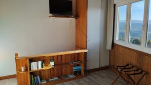 Una habitació amb una biblioteca de fusta, un televisor muntat a la paret i una finestra amb vista a l'exterior.