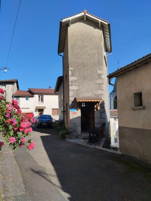 A narrow street with a building featuring a steeply pitched roof and stone walls. - A cozy little nest in the heart of the Bois Noirs (Arconsat)
