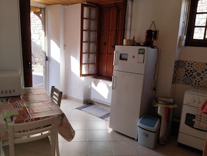 Eine Küche mit Kühlschrank, Herd, Spüle und einem Fenster mit Holzläden.