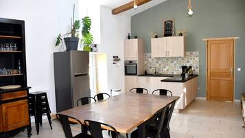 A kitchen with a dining table, chairs, cabinets, a refrigerator, and a potted plant.