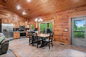 Ein Holzblockhaus-Interieur mit Küche, Essbereich und Blick ins Freie.