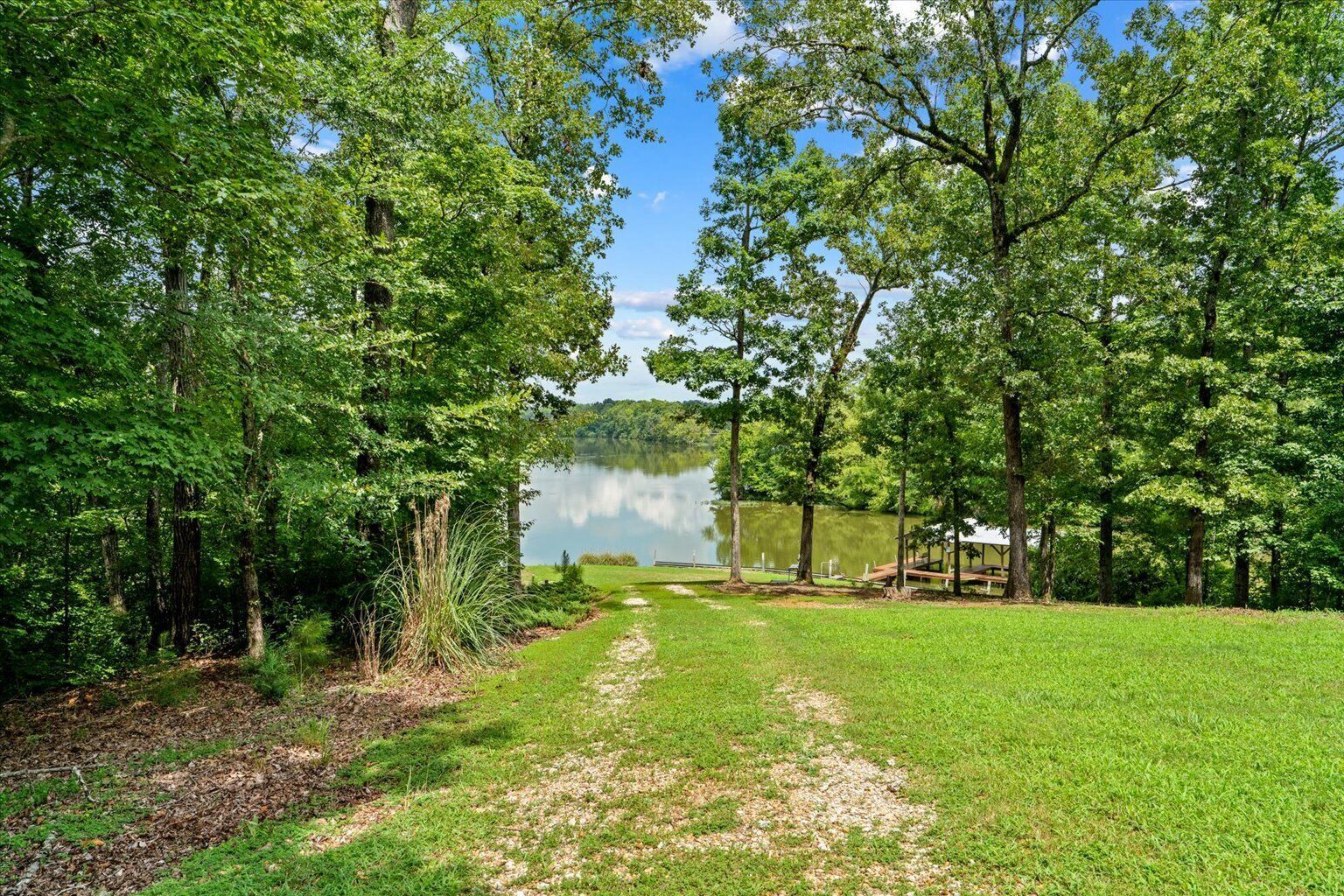 A pathway leading to a lake surrounded by trees.