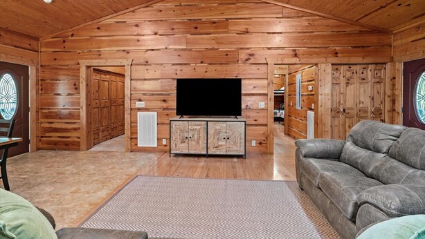 A log cabin interior with a television, sofa, and wooden walls.