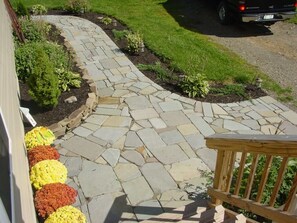 A stone pathway leading to a wooden deck with a vehicle parked nearby. - Stay at the “Farmhand Inn” & live the farm-life while enjoying a great vacation! (Naples)