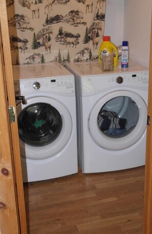 A laundry room with two front-loading washing machines and a wooden floor. - Stay at the “Farmhand Inn” & live the farm-life while enjoying a great vacation! (Naples)