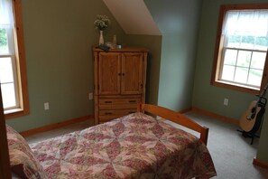 A bedroom with a bed, a wooden dresser, a window, and a guitar. - Stay at the “Farmhand Inn” & live the farm-life while enjoying a great vacation! (Naples)