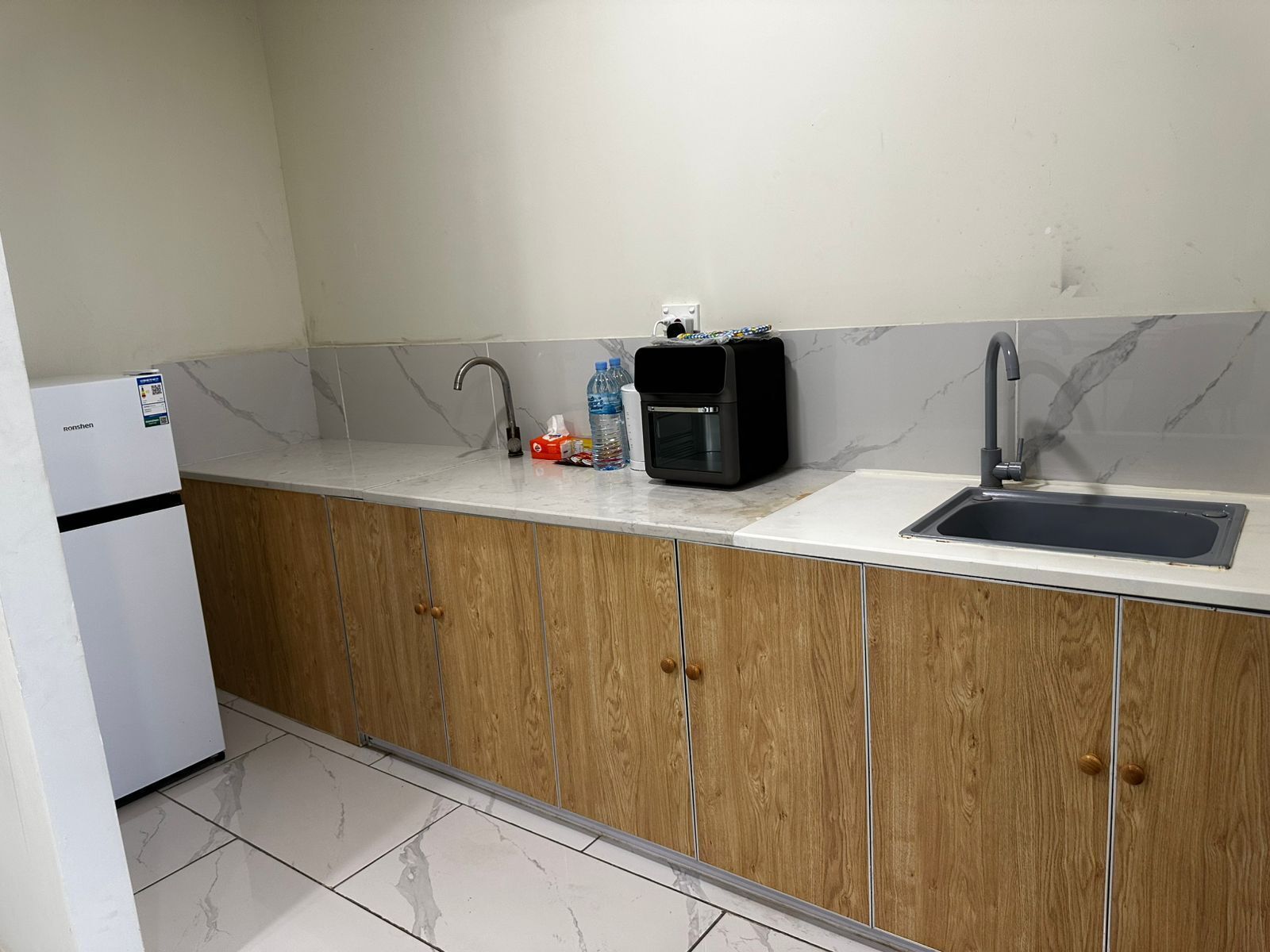 A kitchen with a sink, a coffee machine, and a refrigerator.
