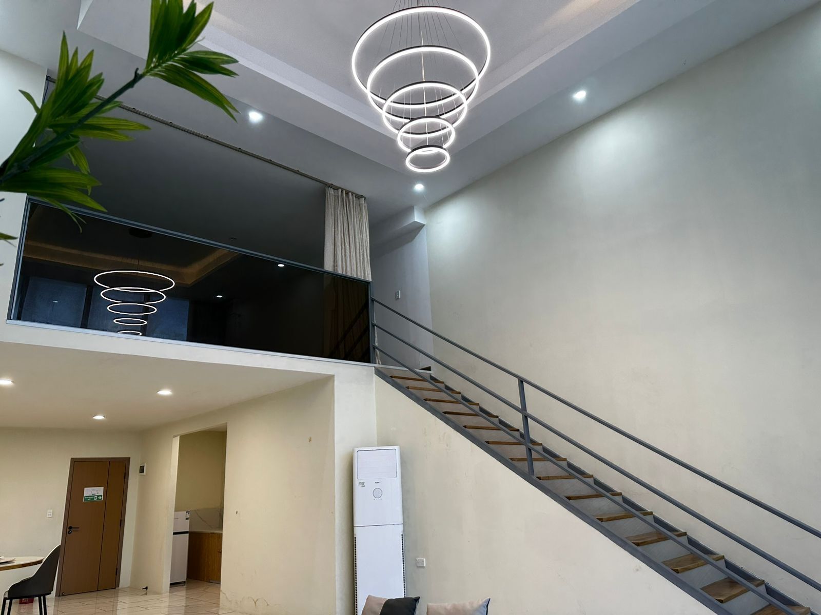 A modern interior with a staircase, a dining area, and a living space with a view.