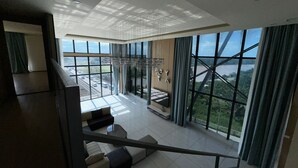 Un amplio salón con ventanas grandes, un techo alto y vistas a un puente y un paisaje.