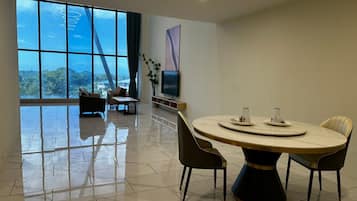 Un comedor moderno con una mesa redonda, sillas, un televisor y vistas al exterior.