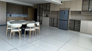Una cocina moderna con una mesa de comedor redonda y sillas, armarios empotrados y un refrigerador de acero inoxidable.