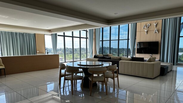 Amplia sala de estar con una mesa de comedor redonda, un sofá y un televisor montado en la pared.