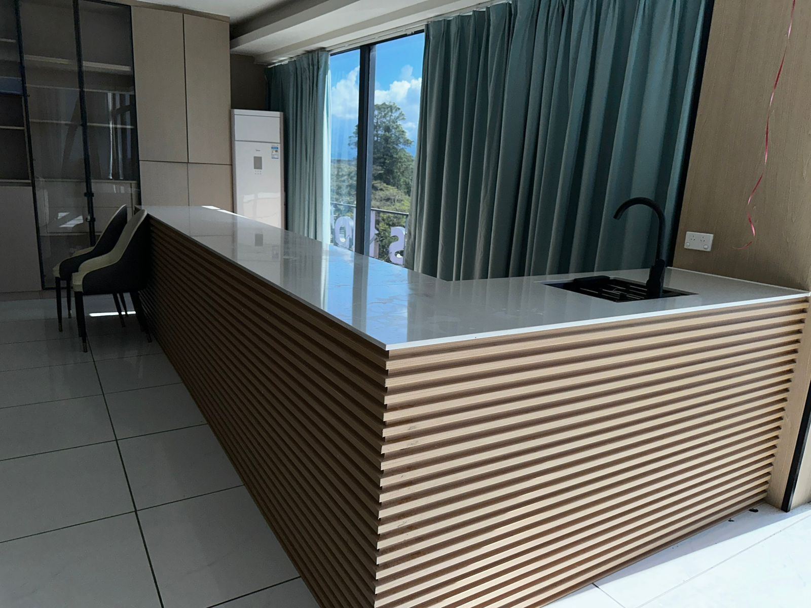 A modern kitchen with a built-in island, a sink, and a window with curtains.