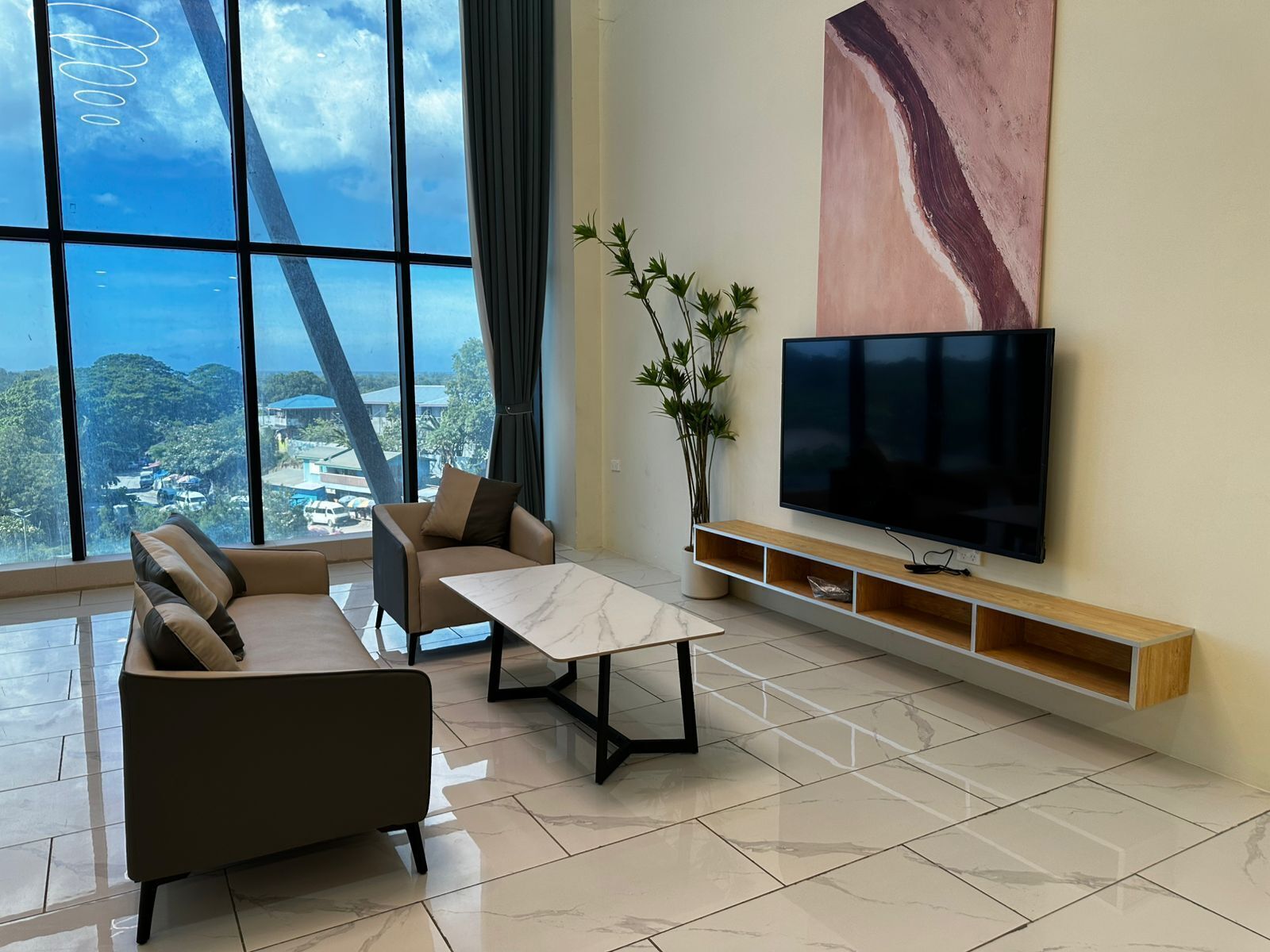 A modern living room with a sofa, coffee table, and a TV on a wall.