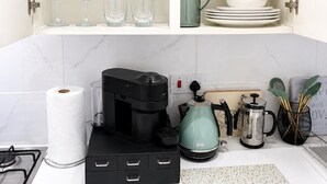 Een keuken met witte kastjes, een koffiezetapparaat, een waterkoker en een theepot.