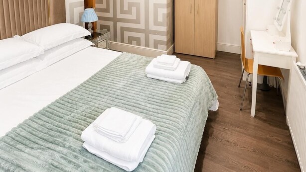 Een netjes ingerichte slaapkamer met een bed, een bureau en een kledingkast.