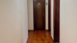 Ein Flur mit einem WC-Schild, einer Lampe und einer Tür mit einem grünen Hinweisschild.