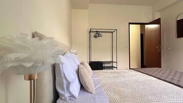 Quarto com cama, mesa de cabeceira, luminária, guarda-roupa e uma porta.