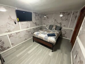 A bedroom with a bed, a flat-screen TV mounted on the wall, and a wooden floor. - Enjoyable 4-bedroom house with AC in charming Big Spring (Big Spring)