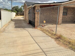 A private property with a gated entrance, a concrete pathway, and a brick building. - Enjoyable 4-bedroom house with AC in charming Big Spring (Big Spring)